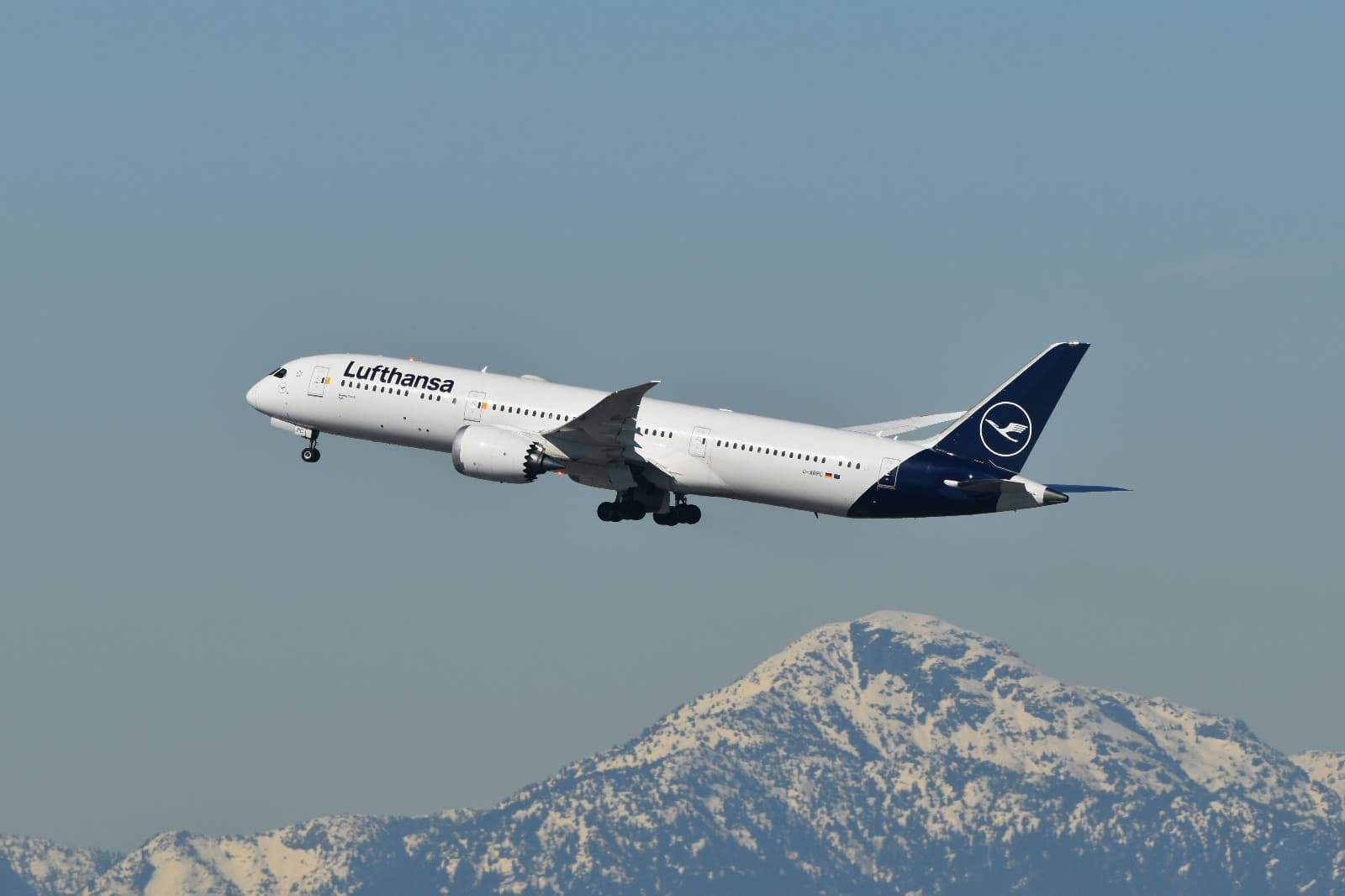 Commercial aircraft climbing after takeoff over mountains